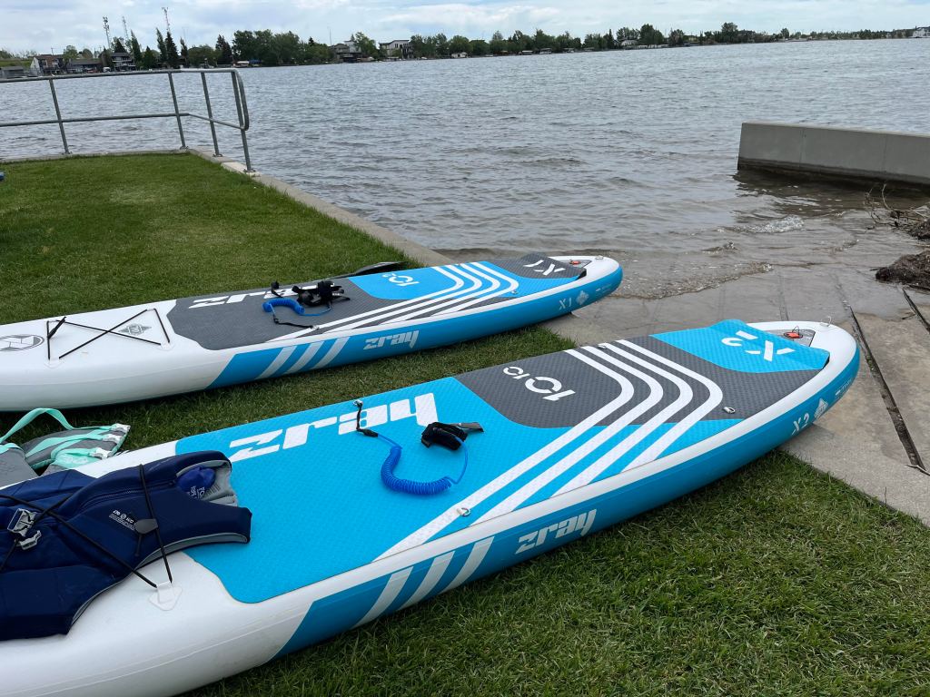 Paddle boards resting on the grass beside the boat launch at Chestermere lake. 